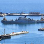 A wide view of the Simon’s Town naval base featuring a Chinese destroyer and an Iranian corvette docked together under the Cape Peninsula mountains