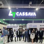 A professional team stands in front of a modern "Cassava Technologies" exhibition booth featuring a green and blue logo, with signs for Liquid Intelligent Technologies and AXON Networks visible in the background.