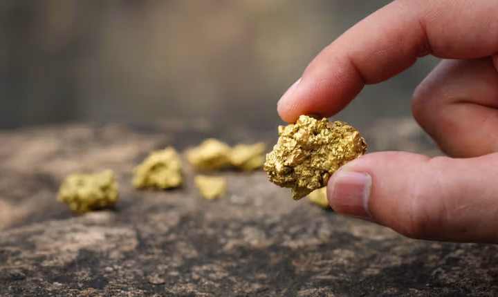 High-quality 3D render of a golden map of Uganda placed on a dark, reflective surface next to several stacked gold bullion bars